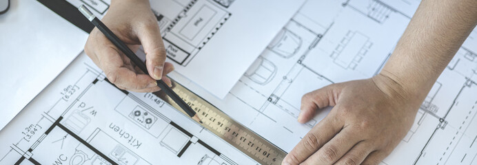 Engineer and Architect concept, Man uses a ruler to measure the floor plan on the blueprint,...