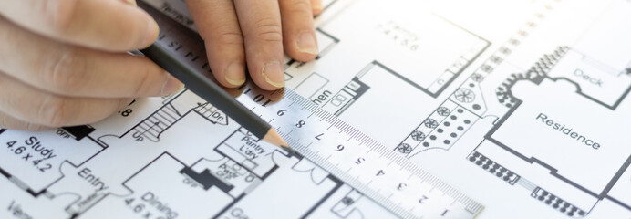 Engineer and Architect concept, Man uses a ruler to measure the floor plan on the blueprint, Building architecture design work, Construction design project under environmental conservation conditions.