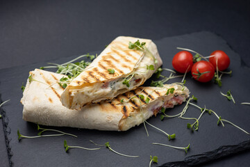 Shawarma with meat and vegetables on a black board
