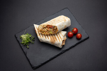 Shawarma with meat and vegetables on a black board
