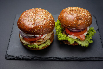 Hamburger on a black board on a black wooden background
