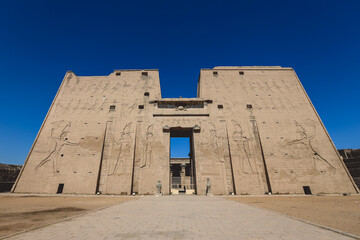 Fototapeta na wymiar View to the main entrance of an Ancient Egyptian Edfu Temple showing the first pylon in the Sunny Day, Egypt