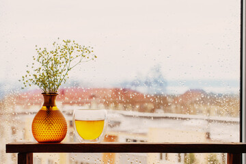 hot tea in thermo glass on background window with raindrops
