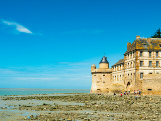 Tourists take a break in the beach surrounding Le Mont Saint Michel during low tide, Normandy,...