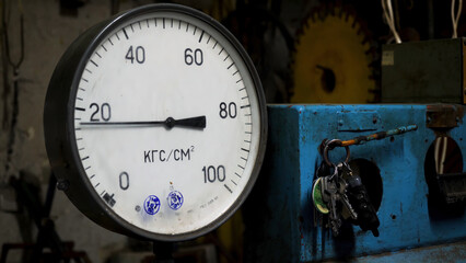 Close up for pressure gauge, measuring instrument at a factory. Manometer with wavering arrow and a bunch of keys hanging near.
