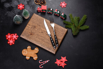 Christmas homemade gingerbread cookies, spices and cutting board on dark background