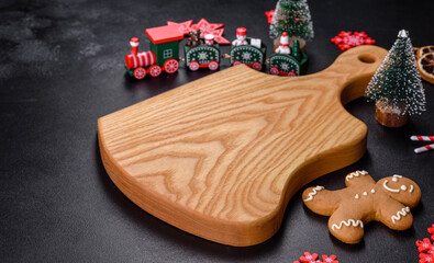 Christmas homemade gingerbread cookies, spices and cutting board on dark background