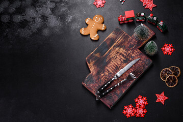 Christmas homemade gingerbread cookies, spices and cutting board on dark background