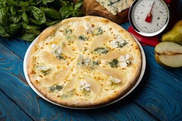 Appetizing baked pizza with white sauce, pear, and gorgonzola cheese on a wooden table. top view