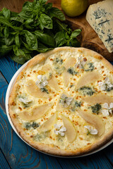 Appetizing baked pizza with white sauce, pear, and gorgonzola cheese on a wooden table. top view
