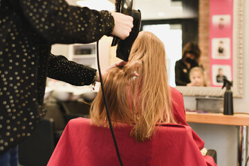 Hairdresser dries hair with a hairdryer at a saon