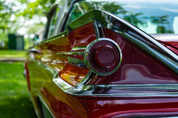 The back of a retro car from the 60s. Rear wing tail unit of red color retro car.