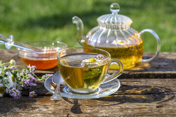 Herbal tea with chamomile and thyme in a transparent cup on an old wooden table on a sunny day