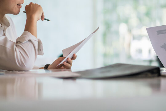 An accountant is examining a large amount of income and expense documents laying on their desks in their offices to summarize their annual results. Accounting concepts to summarize earnings