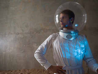 An astronaut on a desert planet alone, an explorer on a distant planet, other worlds and civilizations. A young man in a retrofuturism-style white spacesuit stands on the sand and looks around © Ulia Koltyrina