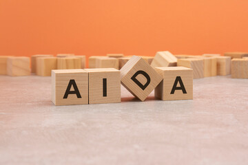 four wooden cubes arranged in line with letters AIDA - meaning Awareness Interest Desire Action - on them, space for text