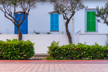 Biała fasada domu z kolorowymi drewnianymi okiennicami. 