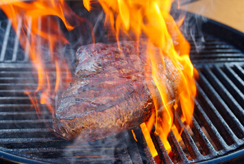 BBQ dry aged wagyu sirloin cap of rump beef steak grilled as close-up on a charcoal grill with fire...