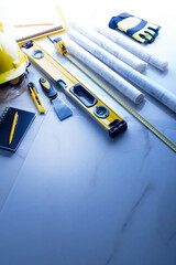 Contractor theme. Plans,  notebook and tool kit of the contractor: yellow hardhat, libella and...