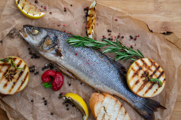 Appetizing sibas fish with greens and vegetables. On a wooden background.