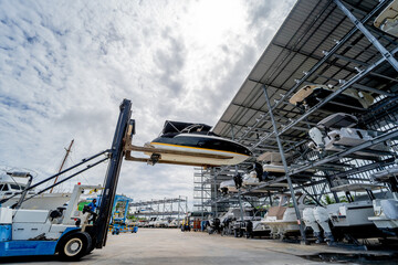 Forklift loading speedboats in a garage system in the marina