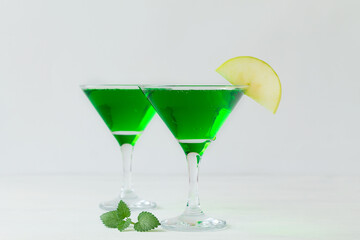 Apple cocktail mixed drink with vodka and apple slice. Apple martini cocktail on the white background. Homemade Green Alcoholic drinks in martini glasses with apple slice. copy space.