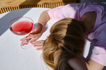 Naklejka premium The girl fell asleep over glasses of red wine. Tasting of alcoholic beverages. Summer rest. Romantic evening aperitif. Close-up of a glass of wine 