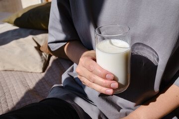 A glass of milk drink or yogurt in the hands of a girl. The concept of lactose intolerance. Transparent glass with tasty milk
