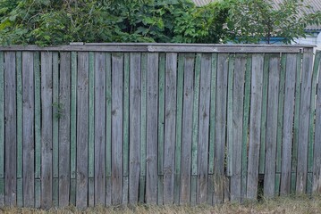 old long green gray wooden wall fence from boards on the rural street