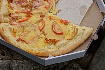 food from piece of fried pizza lies on gray paper packaging box