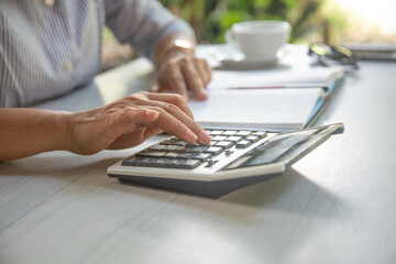 Business woman using calculator finance on wooden desk in home office
