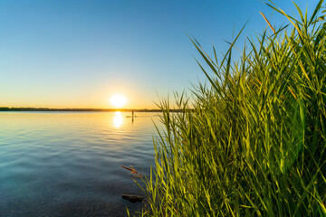 A stand up paddler on a lake at a beautiful sunset