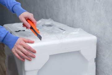 Unpacking large household appliances. Stationery knife hand.