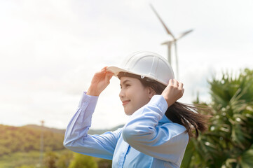 Female engineer working on the seaside wearing a protective helmet over electrical turbines background..
