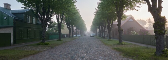 Empty street in a morning fog. Trees, traditional and modern architecture. Ventspils, Latvia....