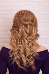 Female back with long curly blonde hair in hairdressing salon