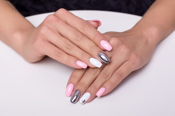 Beautiful female hands with colourful manicure nails, pink and silver colored gel polish
