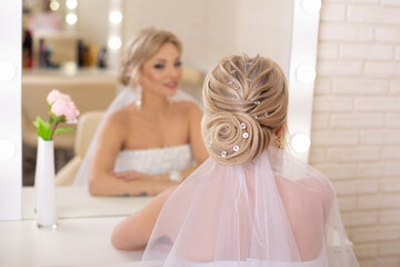 Young beautiful bride with blonde wedding hairstyle and makeup in hairdressing salon