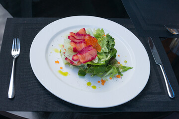 Red caviar and marinated salmon in a salad. Delicious healthy salad with salmon, cucumber and Lactuca leaves on a plate. Proper nutrition. Romantic dinner.