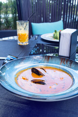 Delicious seafood tomato bouillabaisse fish soup with shrimps, mussels and fish in a blue plate on...