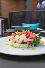 Red caviar and marinated salmon in a salad. Delicious healthy salad with salmon, cucumber and Lactuca leaves on a plate. Proper nutrition. Romantic dinner.