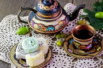 Colorful teapot with a cup and sweets on a napkin on the table.