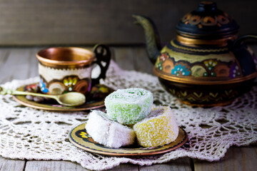Colorful tea set of a teapot and a cup with sweets on the table.