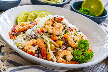 Spaghetti with prawns and parmesan on wooden table
