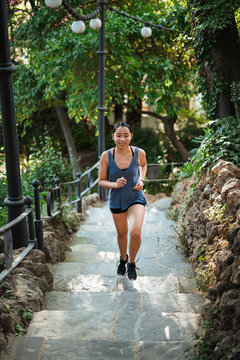 Asian fitness girl running up stone stairs in the park