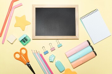 Background with school material, on yellow background. Blackboard for text. Accessories with pastel colours.