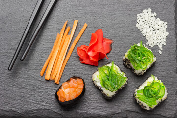 Sushi with seaweed, sliced carrots, ginger on stone board
