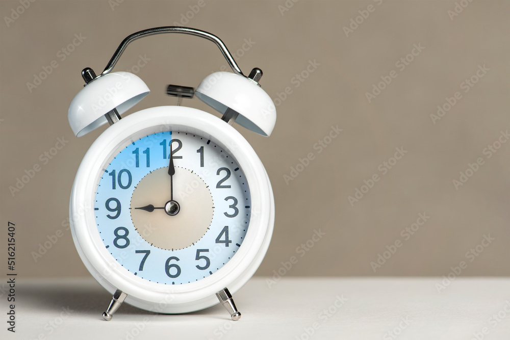 Fototapete Nine o'clock on the alarm. A white alarm clock is on a white table. The clock hand points to 9 o'clock. Time to change to summer or winter time. Set an alarm for 9:00 or 21:00. copy space