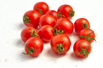 Group of red cherry tomatoes, ripe organic tomatoes on a light wooden background