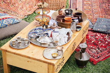 Tea ceremony at the Crimean Tatars, a table with a teapot, cups and food on red carpets